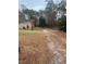 View of the property with a gravel driveway and lush surrounding trees at 129 Jeffress Dr, Louisburg, NC 27549