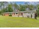 Attractive brick and stone home with a green front lawn, set against a backdrop of lush trees at 129 Jeffress Dr, Louisburg, NC 27549