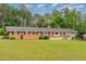 Inviting brick and stone home with black shutters, a manicured lawn, and a tree-lined backdrop at 129 Jeffress Dr, Louisburg, NC 27549