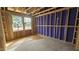 Unfinished bedroom featuring stud framing, plywood subfloor, two windows offering natural light, and exposed roof rafters at 3934 Well Fleet Drive, Fuquay Varina, NC 27526