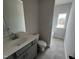 An unfinished bathroom features gray cabinets, a large mirror, and a window above the bathtub at 165 Knoll Way, Sanford, NC 27332