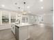 Bright living room with hardwood floors connected to an open kitchen, large windows, and neutral color palette at 906 Brookfield Dr, Gibsonville, NC 27249