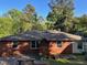 The rear of the brick home features a backyard with a small wooden deck, garden area, and mature trees at 2705 Royster St, Raleigh, NC 27608
