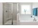 Bathroom featuring a walk-in shower, soaking tub, and tiled accents for a spa-like experience at 596 Ravensworth Dr, Garner, NC 27529