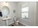 Well-lit powder room with a pedestal sink, an oval mirror, and a window at 596 Ravensworth Dr, Garner, NC 27529