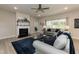 A cozy living room with a fireplace, large windows, a ceiling fan, gray sofas, and neutral walls at 596 Ravensworth Dr, Garner, NC 27529
