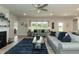 Bright living room with a ceiling fan, a fireplace, sofas, and a glass coffee table on a blue rug at 596 Ravensworth Dr, Garner, NC 27529