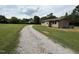 Gravel driveway leading to a cozy home with a well-maintained lawn and surrounding trees at 2253 Nc Highway 96 S, Franklinton, NC 27525