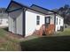 Exterior side view of a bright white siding home featuring a stained wooden porch, black trim and a green yard at 4553 Dedication Dr, Raleigh, NC 27610