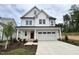 Charming two-story home featuring a red front door, white siding, and an attached two-car garage at 105 Windchime Ct, Fuquay Varina, NC 27526