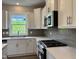 Modern kitchen with white cabinets, quartz countertops, a gray backsplash, and stainless steel appliances at 105 Windchime Ct, Fuquay Varina, NC 27526