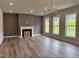 Spacious living room with a fireplace, mantel, three large windows and modern light fixture at 105 Windchime Ct, Fuquay Varina, NC 27526