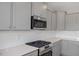 Close-up of a kitchen with gray cabinets, white backsplash, quartz countertop and stainless steel appliances at 3856 Well Fleet Drive, Fuquay Varina, NC 27526