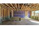 Unfinished living room featuring exposed framing, utilities, and a sunlit view through the windows at 3858 Well Fleet Drive, Willow Springs, NC 27592