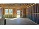Partially completed living room showcasing exposed framing, windows, and doorway overlooking outdoor greenery at 3858 Well Fleet Drive, Willow Springs, NC 27592