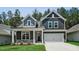 Charming two-story home featuring a two-car garage, gray siding, stone accents, and a well-manicured lawn at 7537 Percussion Dr, Apex, NC 27539