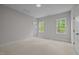 Bright bedroom with neutral walls, carpet, and two windows offering a view of the trees outside at 7813 Ailesbury Rd, Wake Forest, NC 27587