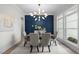 Sophisticated dining area with a unique light fixture, comfortable seating, and a vibrant blue accent wall at 7813 Ailesbury Rd, Wake Forest, NC 27587