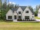 A beautiful two-story, white brick home with dark trim surrounded by a lush green lawn and mature trees at 7813 Ailesbury Rd, Wake Forest, NC 27587