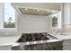 Close up view of the gourmet range with stainless steel hood, custom backsplash, and bright windows in the kitchen at 2908 Frances Marie Ln, Raleigh, NC 27603