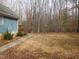 Home's backyard with wooded area and walkway at 513 Port Dr, Henderson, NC 27537
