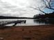 Calm lake view with sandy shoreline and a wooden dock at 513 Port Dr, Henderson, NC 27537