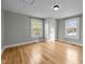 Bright bedroom with hardwood floors, complemented by light gray walls and abundant natural light from two windows at 826 Carter Ave, Durham, NC 27703