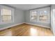 Simple bedroom with hardwood floors, gray walls, and two windows at 826 Carter Ave, Durham, NC 27703