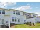 Rear exterior view of a townhouse showcasing white siding, fenced yard and well-manicured lawn at 43 Honeydew Way, Clayton, NC 27520