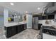 Open kitchen with stainless steel appliances, black cabinets, and a pass-through to the living room at 5705 Katha Dr, Holly Springs, NC 27540