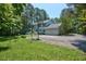 Exterior view of the home with a spacious driveway, lush lawn, mature trees, and a basketball hoop at 340 Andrews Store Rd, Pittsboro, NC 27312