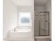 Bathroom featuring a tiled shower with glass door, a soaking tub, and a window at 534 Glenkirk Pl # 110, Garner, NC 27529