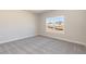 An empty bedroom has neutral colored walls, carpet, and a window overlooking neighboring houses at 563 Glenkirk Pl # 104, Garner, NC 27529
