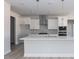 Modern kitchen with white cabinetry, stainless steel appliances, and a large island with quartz countertops at 563 Glenkirk Pl # 104, Garner, NC 27529