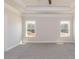 Spacious main bedroom with plush carpeting, tray ceilings, and two large windows at 563 Glenkirk Pl # 104, Garner, NC 27529