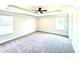 Spacious bedroom featuring a ceiling fan, two windows, neutral walls, and plush gray carpeting at 211 Drayton Hall Ln, Sanford, NC 27330