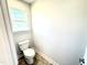 Neat half bathroom featuring neutral walls, tile flooring, a standard toilet, and a window at 211 Drayton Hall Ln, Sanford, NC 27330