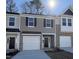 Two-story townhome with gray siding, white garage doors, and landscaping at 6336 Lady Eliza Ln, Raleigh, NC 27610