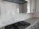 Close up of kitchen gas cooktop and white backsplash at 5168 Church Rd # 22, New Hill, NC 27562