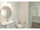 Powder room featuring a pedestal sink, round mirror, and modern fixtures at 587 Glenkirk Pl, Garner, NC 27529