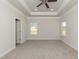 A spacious main bedroom features neutral walls, tray ceiling, a ceiling fan, carpet flooring, and two windows at 587 Glenkirk Pl, Garner, NC 27529