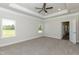 A spacious main bedroom features neutral walls, tray ceiling, a ceiling fan, carpet flooring, and two windows at 587 Glenkirk Pl, Garner, NC 27529