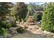 Secluded backyard oasis with lush landscaping, stone patio, dining area, and seating, great for outdoor living at 2526 Snowdrop Ct, Apex, NC 27502