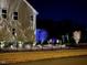 Home exterior illuminated with dramatic landscape lighting on the trees and shrubs at 2526 Snowdrop Ct, Apex, NC 27502