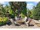 Outdoor stone fire pit area with chairs and lush landscaping creates a cozy gathering space at 2526 Snowdrop Ct, Apex, NC 27502