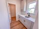 The laundry room features white cabinets, countertops, stainless sink and hardwood flooring at 403 Duncan Creek Rd # 131, Lillington, NC 27546