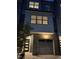 Modern townhome with a gray garage door and brick accents, illuminated by an outdoor light fixture at 702 Portia Way, Homesite 16, Morrisville, NC 27560
