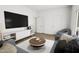 Modern living room with a large TV, sleek white shelving and gray couches at 702 Portia Way, Homesite 16, Morrisville, NC 27560