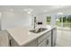 Open concept kitchen island featuring a stainless steel sink, quartz countertops, and backyard views at 261 Kissington Way, Benson, NC 27504