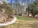 Grassy backyard featuring a sidewalk surrounded by a tree line, providing plenty of space and shade at 4701 Regalwood Dr, Raleigh, NC 27613